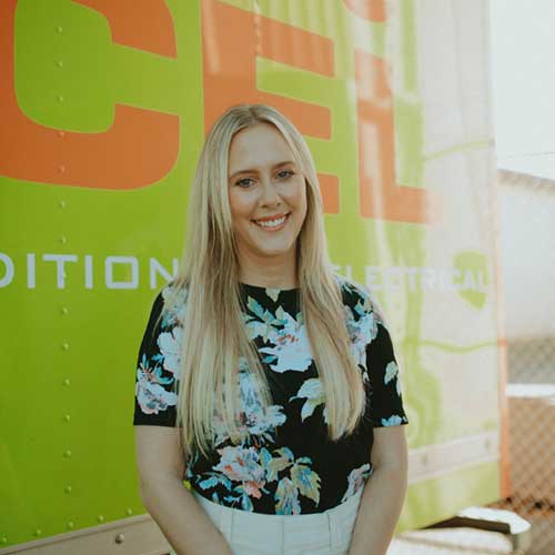 ServiceXEL team member in floral top smiling in front of branded green and orange service vehicle