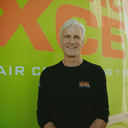 ServiceXEL team leader smiling in front of branded green and orange company background