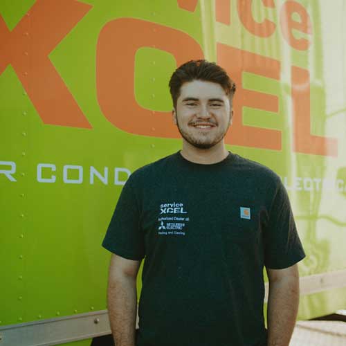 ServiceXEL team member smiling in front of a branded green company van